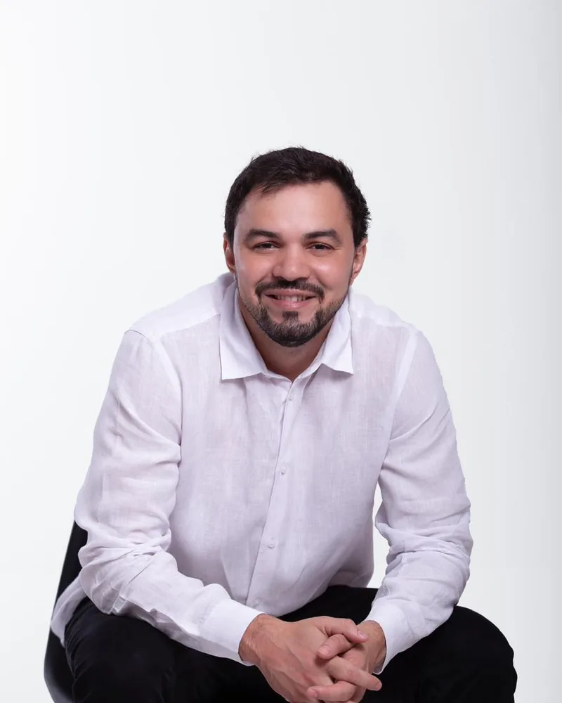Dr. Firminio Humberto sentado, sorrindo, de camisa branca