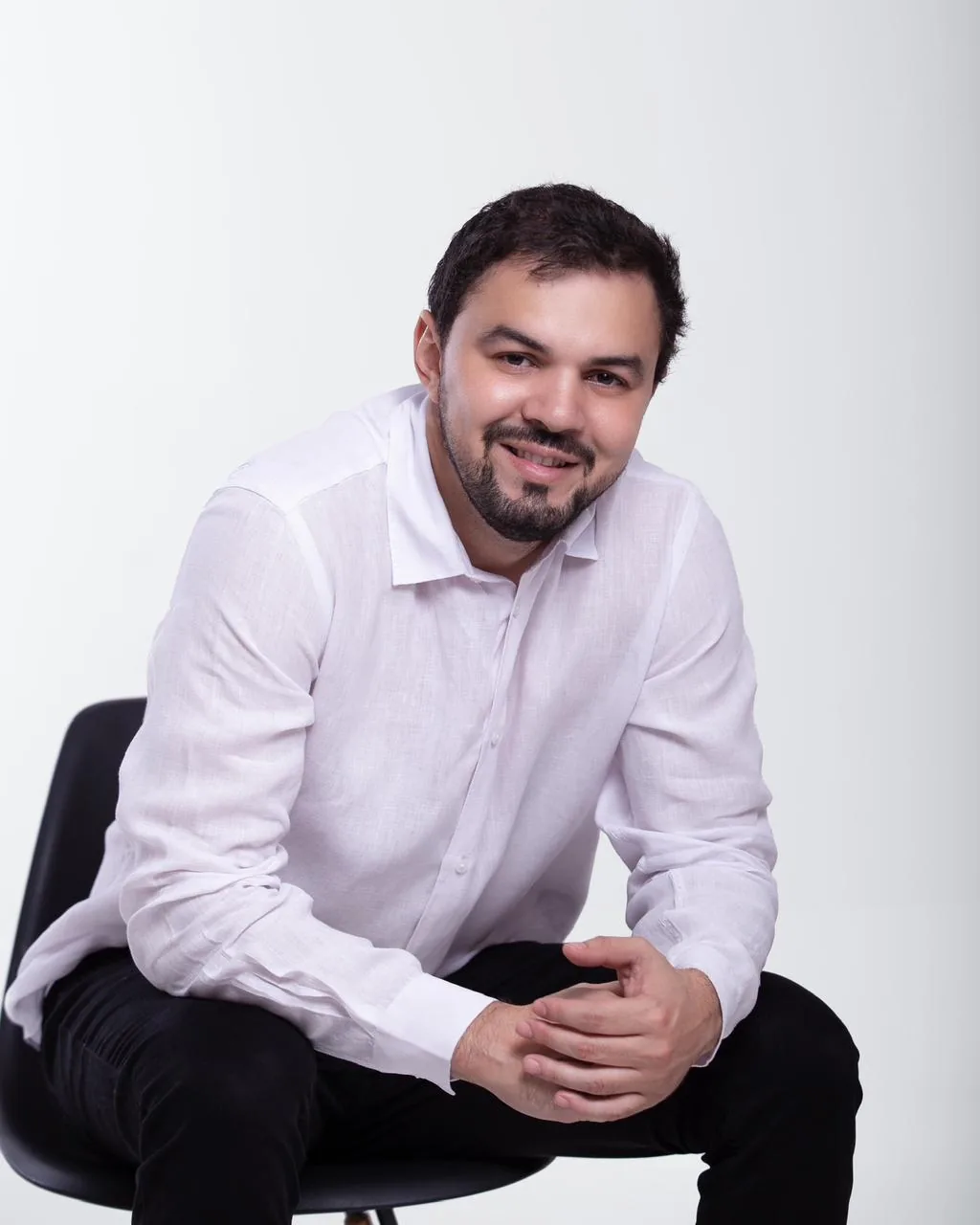 Dr. Firminio Humberto sorrindo, sentado, de camisa branca
