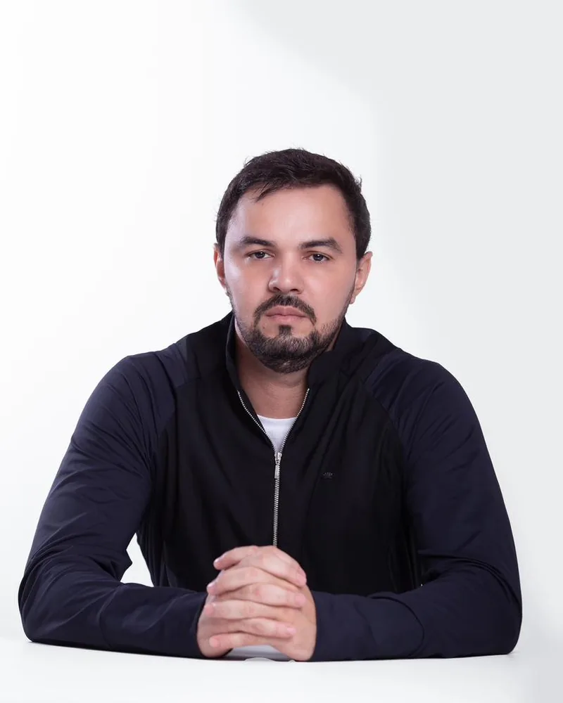 Dr. Firminio Humberto sentado à mesa, de jaqueta escura