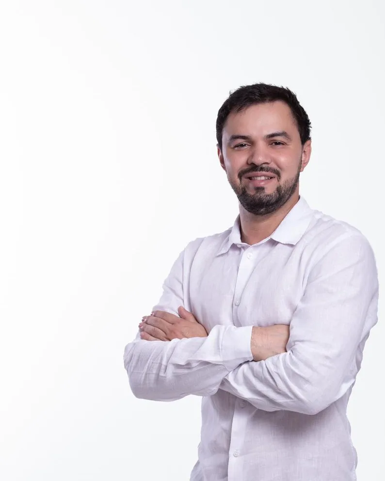 Dr. Firminio Humberto em pé, de braços cruzados, sorrindo