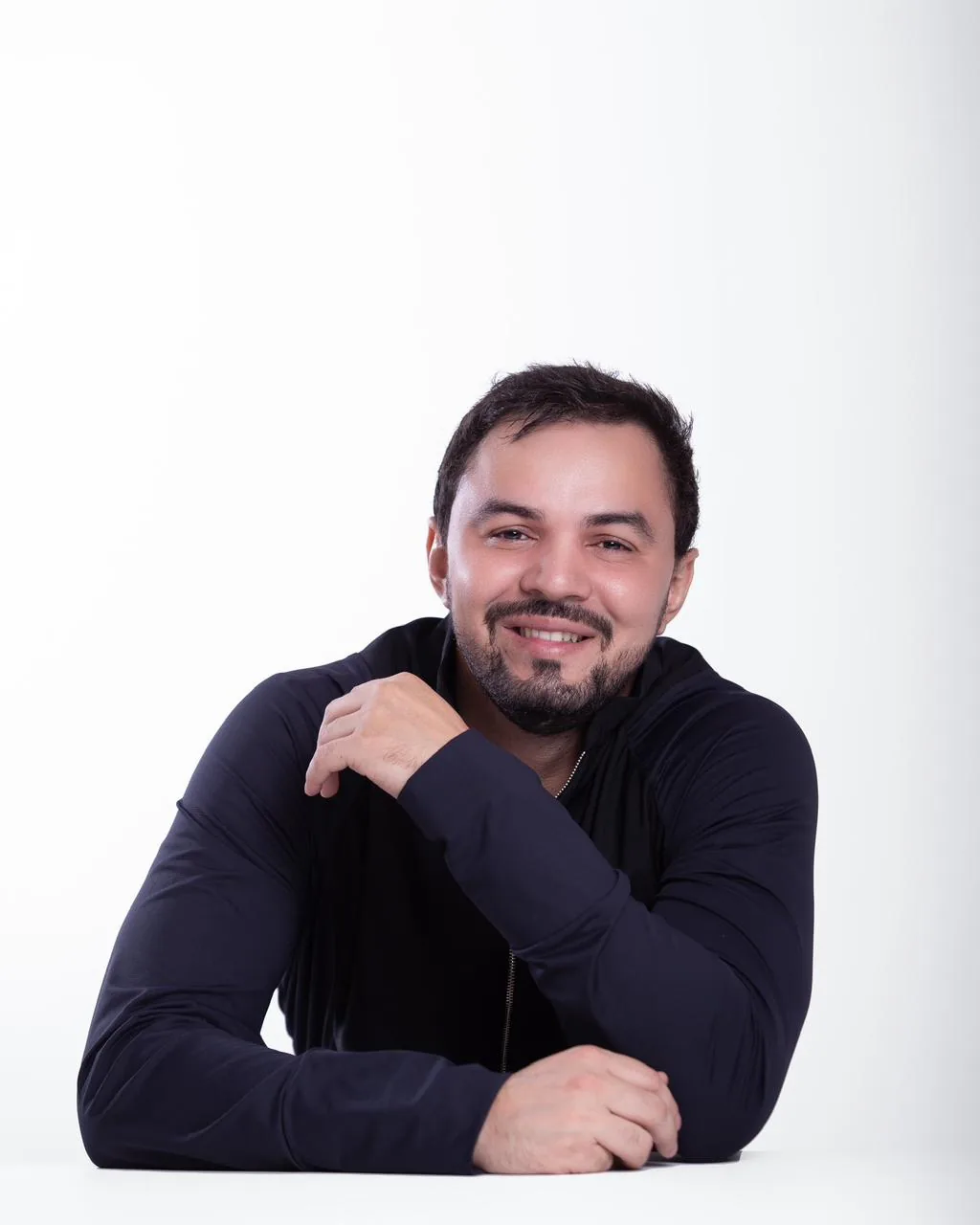 Dr. Firminio Humberto sorrindo, de jaqueta escura, apoiado em uma mesa